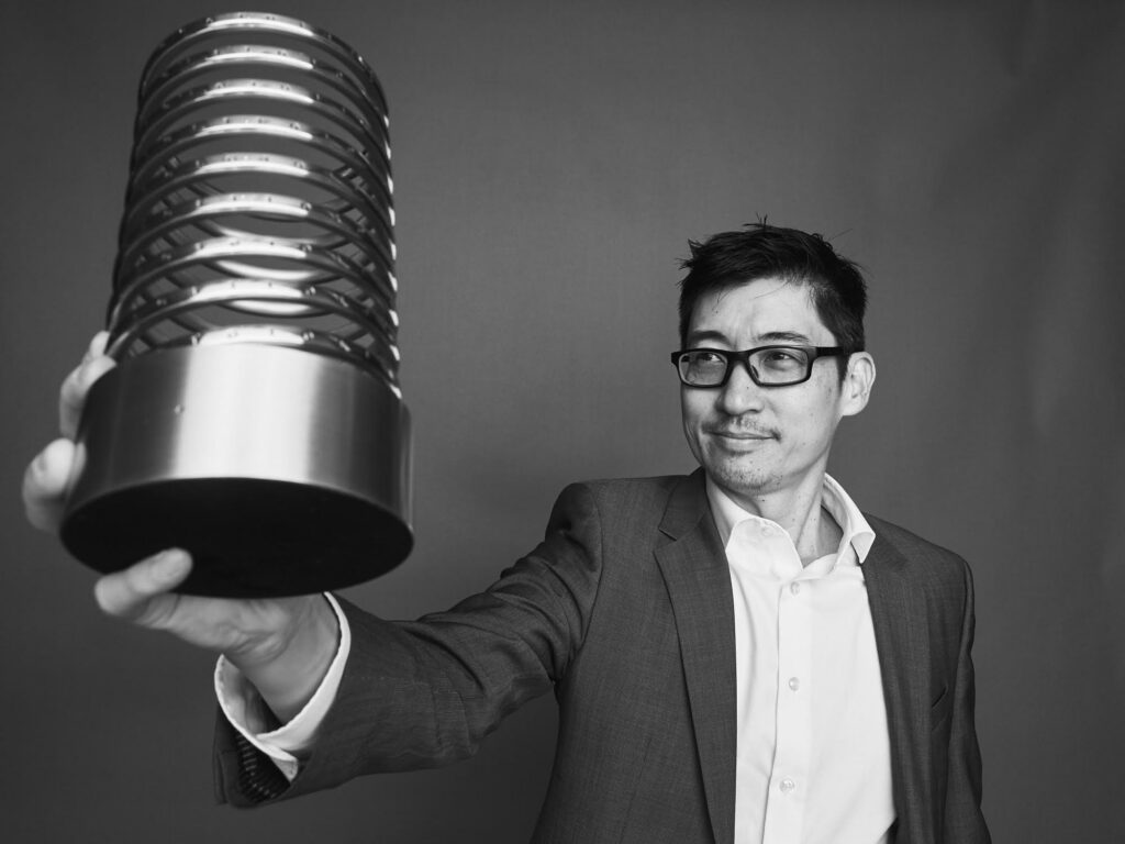 A photograph of Thomas Lin holding a Webby Award.