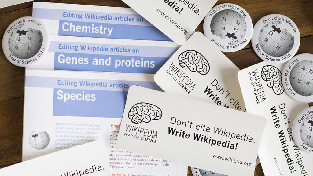 A collection of Wikipedia Year of Science paraphernalia: fliers, stickers and pins