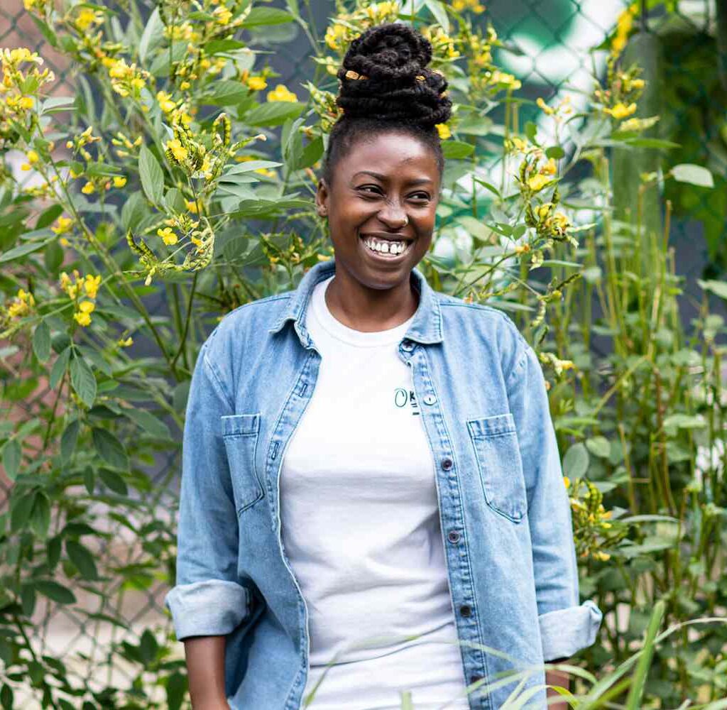 Yemi Amu standing in front of a bushel of flowers