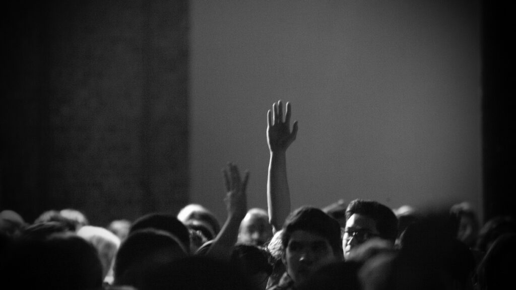 Heads of a crowd with two people's hands raised