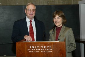 Two people in business attire stand behind a podium that reads Institute for Advanced Study, Princeton, New Jersey, smiling at the camera.