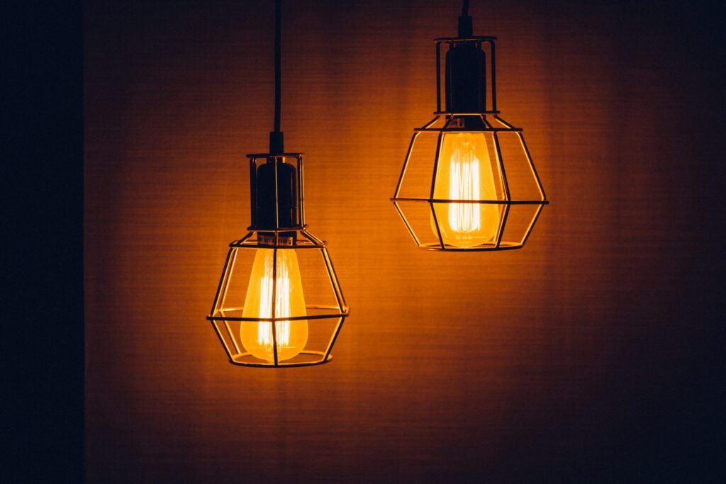 Two similar-looking lightbulbs shine while hanging from the ceiling.