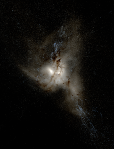 A bright, irregularly shaped galaxy with glowing white and blue areas, surrounded by dark dust lanes, set against a black background filled with tiny stars.