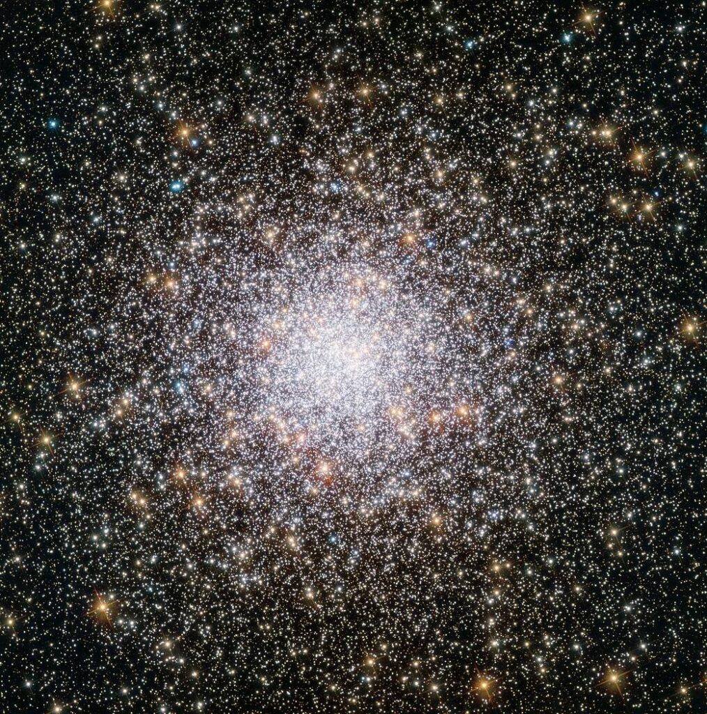 A dense cluster of thousands of stars tightly packed together, glowing brightly against a dark space background, with stars scattered more sparsely toward the edges.