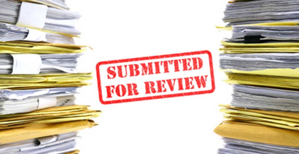 Two tall stacks of paperwork with a red SUBMITTED FOR REVIEW stamp in the center against a white background.