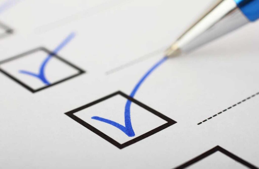 A close-up of a checklist with blue checkmarks in boxes and a pen marking one of the boxes.