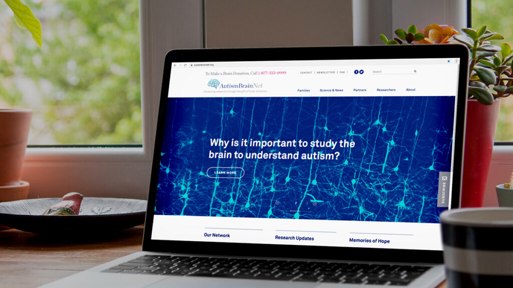 A laptop on a table displays a website about autism brain research with the text, Why is it important to study the brain to understand autism? on the screen.