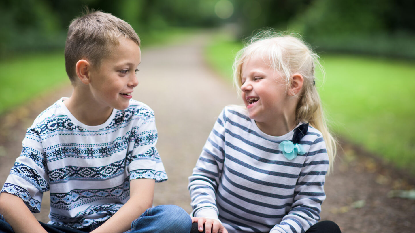 A little boy with Autism and his sister sitting playing together laughing and being happy, smiling and cute.