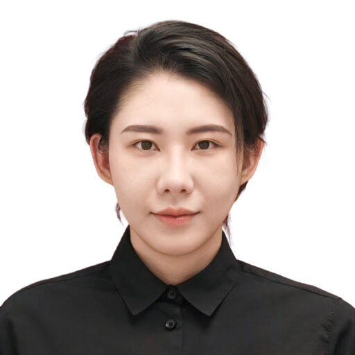 A person with short black hair wearing a black collared shirt, facing forward and looking at the camera with a neutral expression against a plain white background.