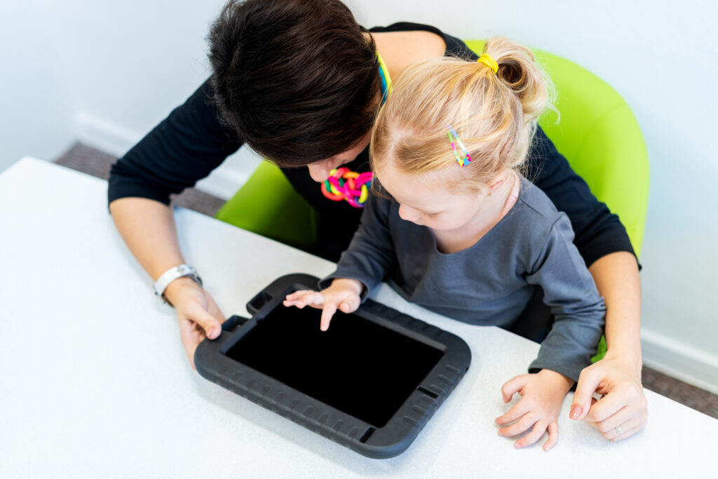 Woamn helping a child learn with tablet.