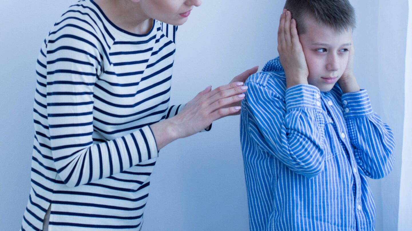 Photo of Boy with autism spectrum disorder covers his ears during a therapeutic session.