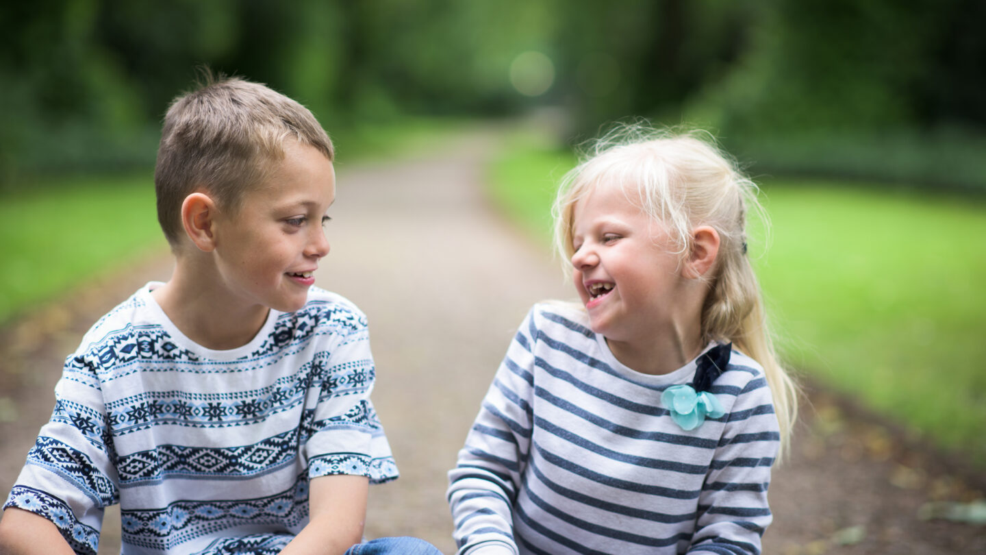 A little boy with Autism and his sister sitting playing together laughing and being happy, smiling and cute.
