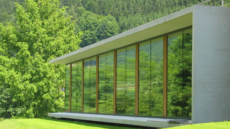 A photo of the north side library extension at the Mathematisches Forschungsinstitut Oberwolfach (MFO, Oberwolfach Research Institute for Mathematics) showing a mostly glass building in a green landscape.