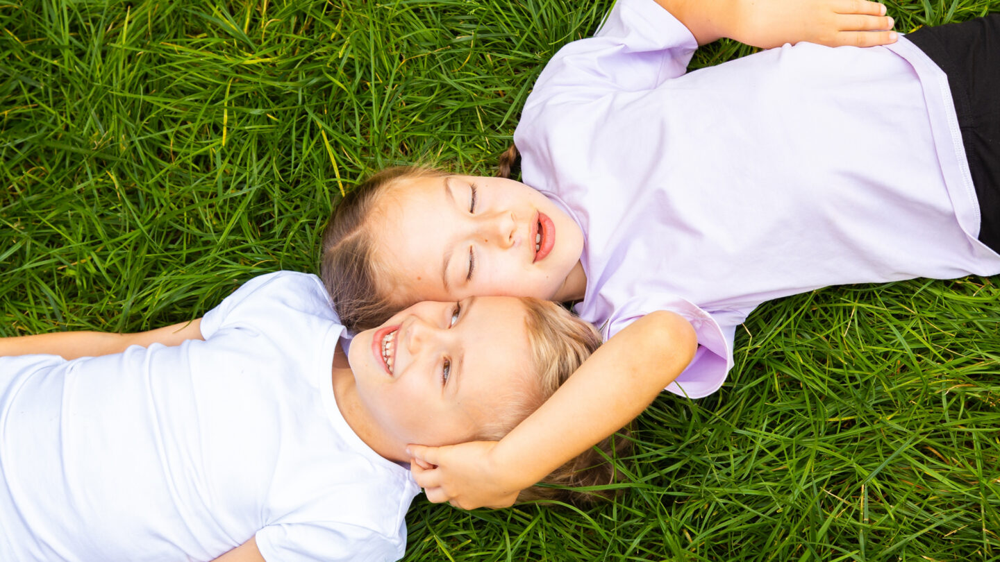 A photo of a boy and girl child lying in the gras.