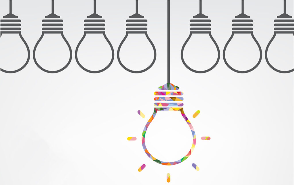 A row of outlined light bulbs hangs, with one colorful bulb in the center glowing, symbolizing creativity and standing out from the crowd.