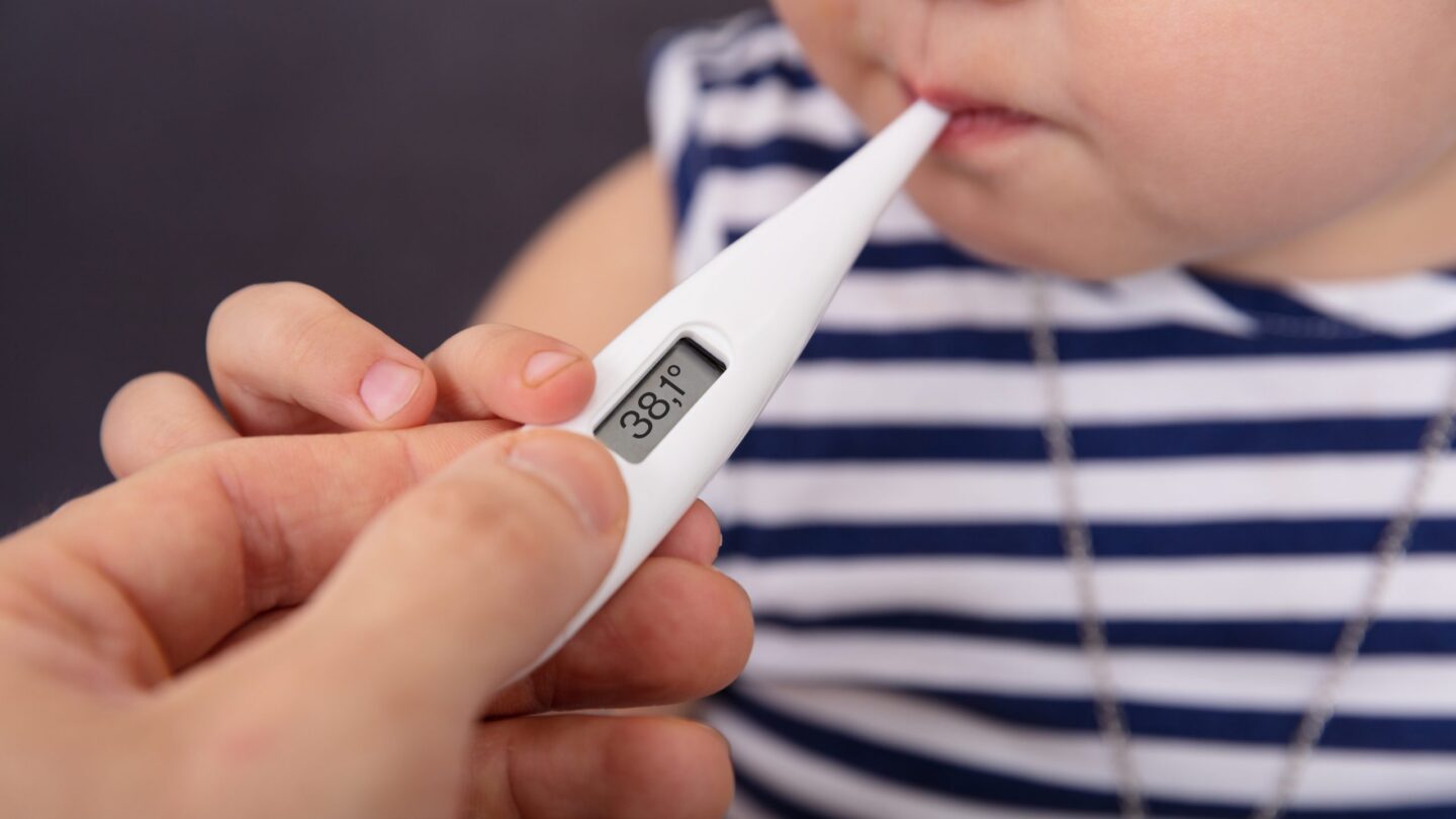 Person's Hand Checking Fever Of Sick Girl