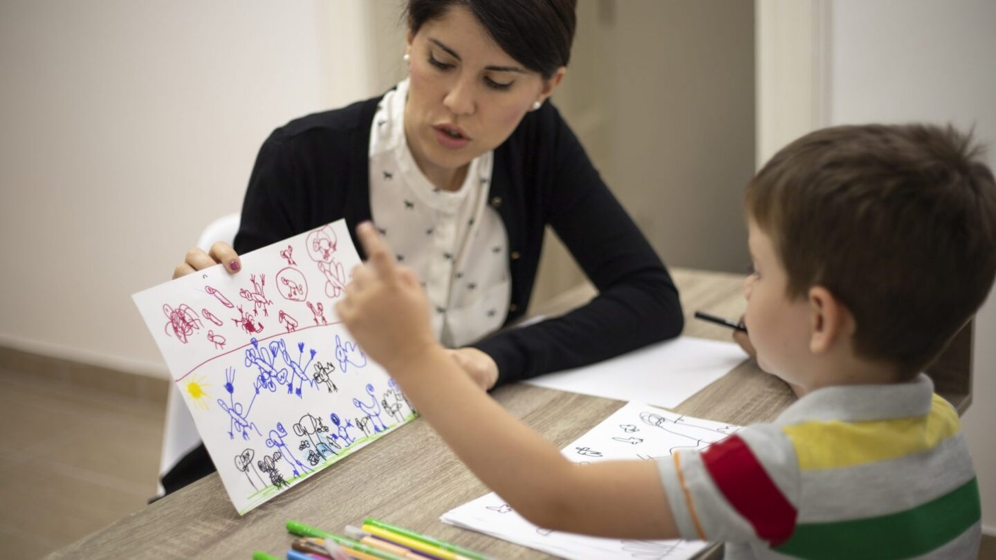 Image of boy showing drawing to woman