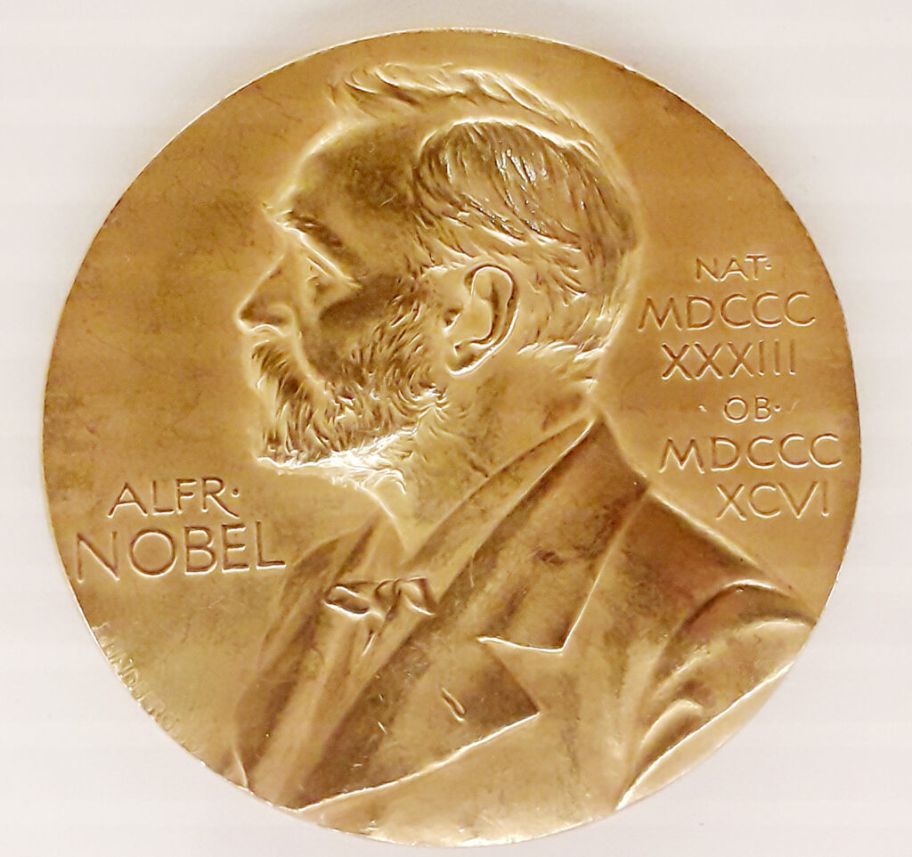 Gold Nobel Prize medal featuring the profile of Alfred Nobel, with his name and Roman numerals inscribed on the left and right sides.