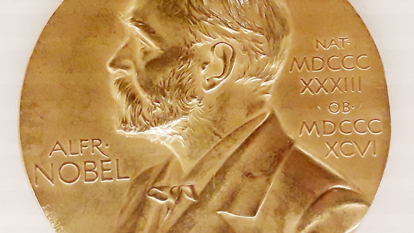 Gold Nobel Prize medal featuring the profile of Alfred Nobel, with his name and Roman numerals inscribed on the left and right sides.