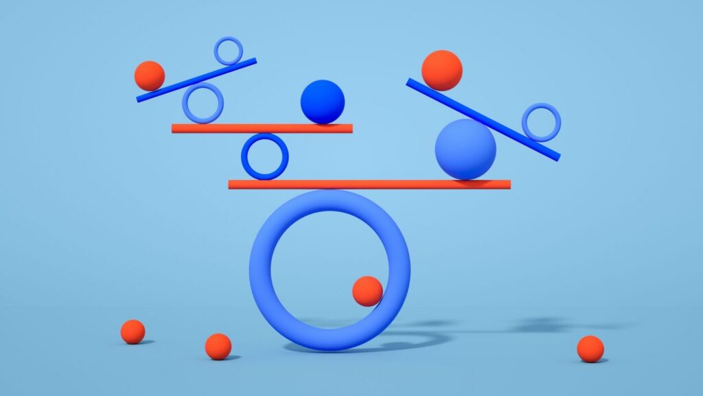 Blue and orange spheres and rings are balanced on see-saw-like planks against a light blue background, creating an abstract, symmetrical composition.