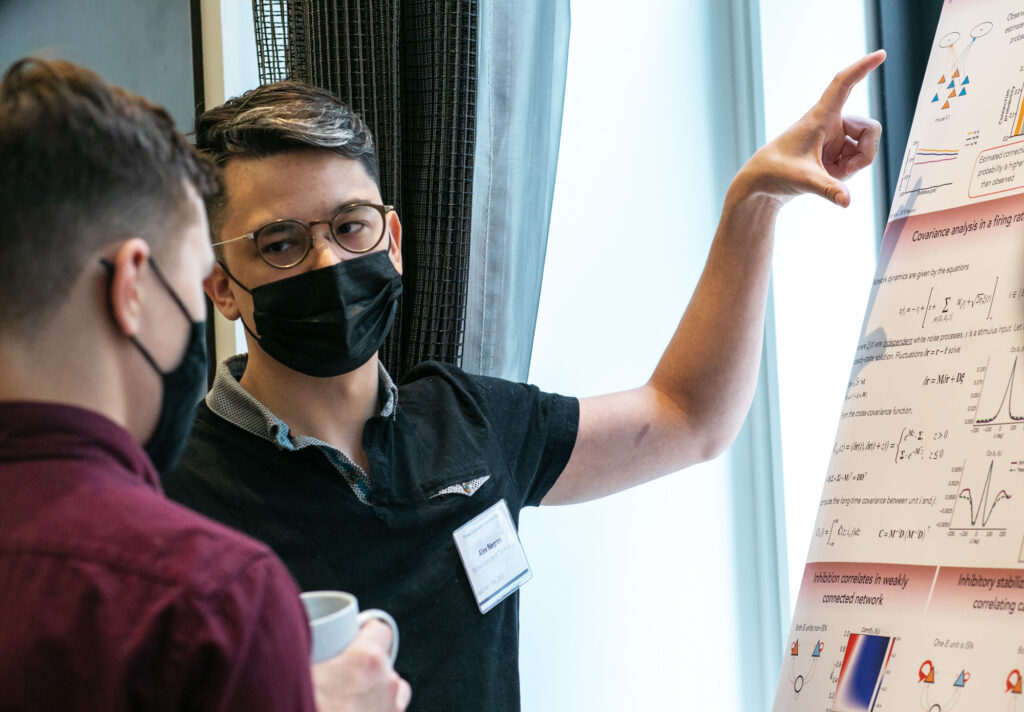 A photo of Alex Negrón, wearing a COVID-19 mask, presenting his poster at the SURFiN Symposium.