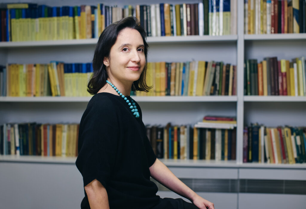 A photo of Pilar Cossio sitting in front of a shelf of math books.