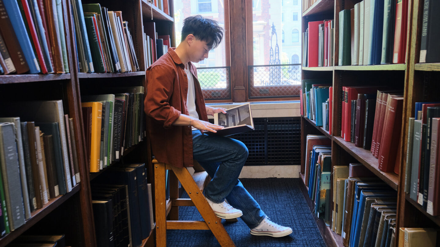 Photo of Kevin Hu sitting in the library at Columbia University