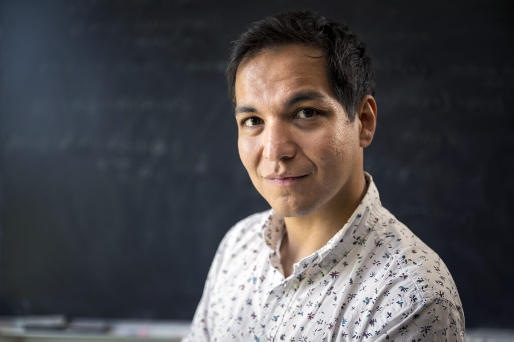 A portrait of Axel in a short sleeve white shirt smiling at the camera.