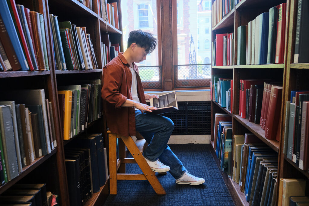 Photo of Kevin Hu sitting in the library at Columbia University