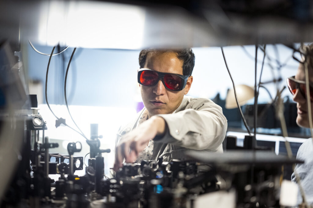 A photo of Axel working on his lab equipment with protective goggles on.