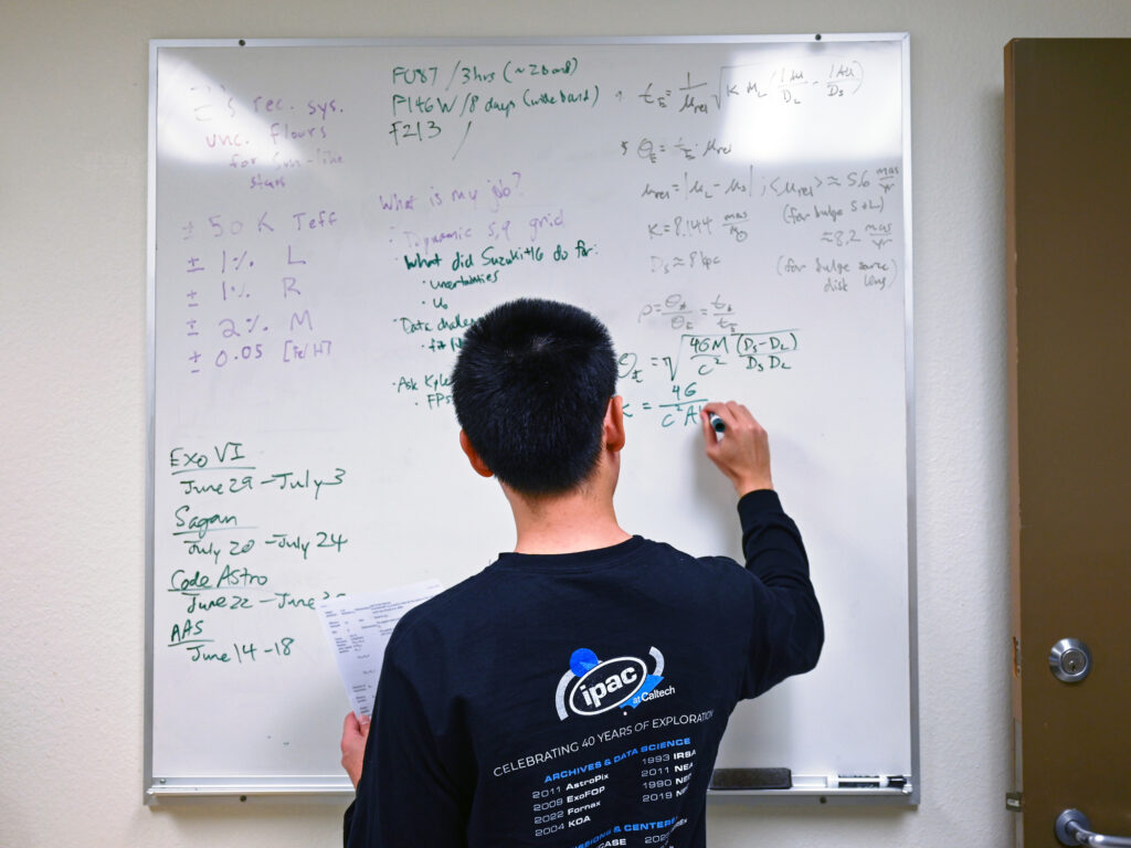 A photo of Chris Lam working at a whiteboard in ipac.