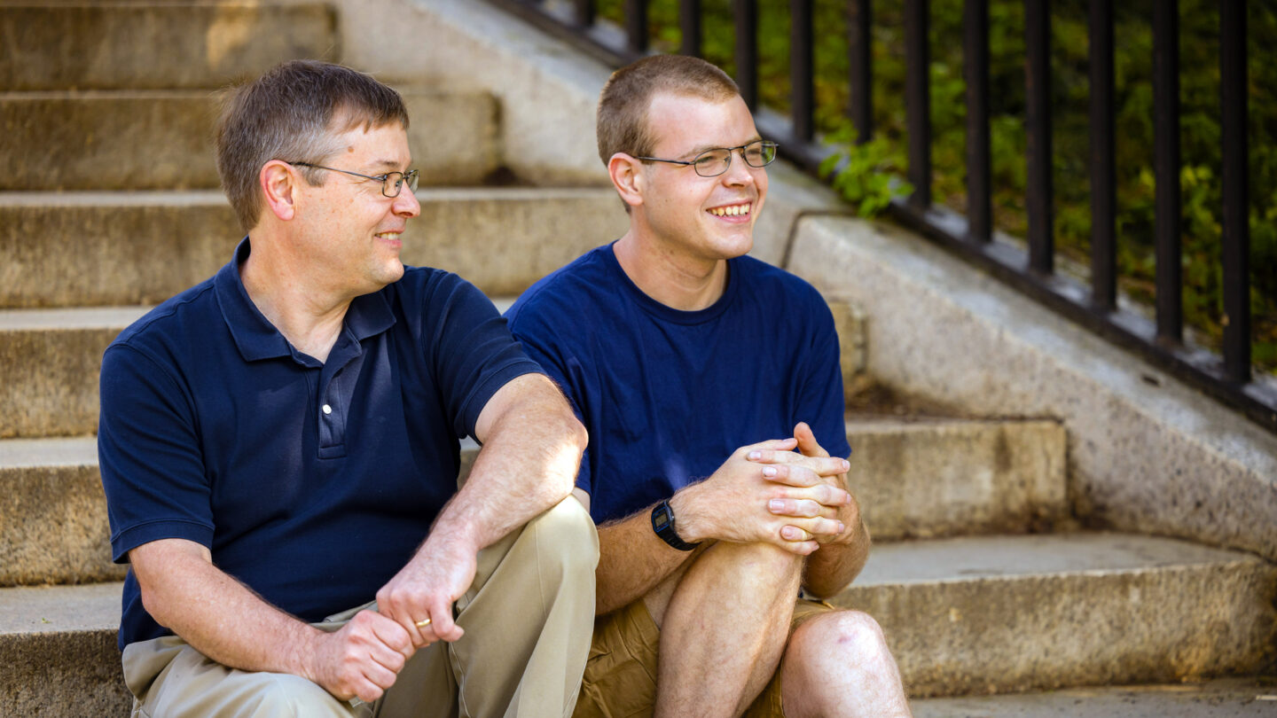 A photo of a father and son sitting on steps.