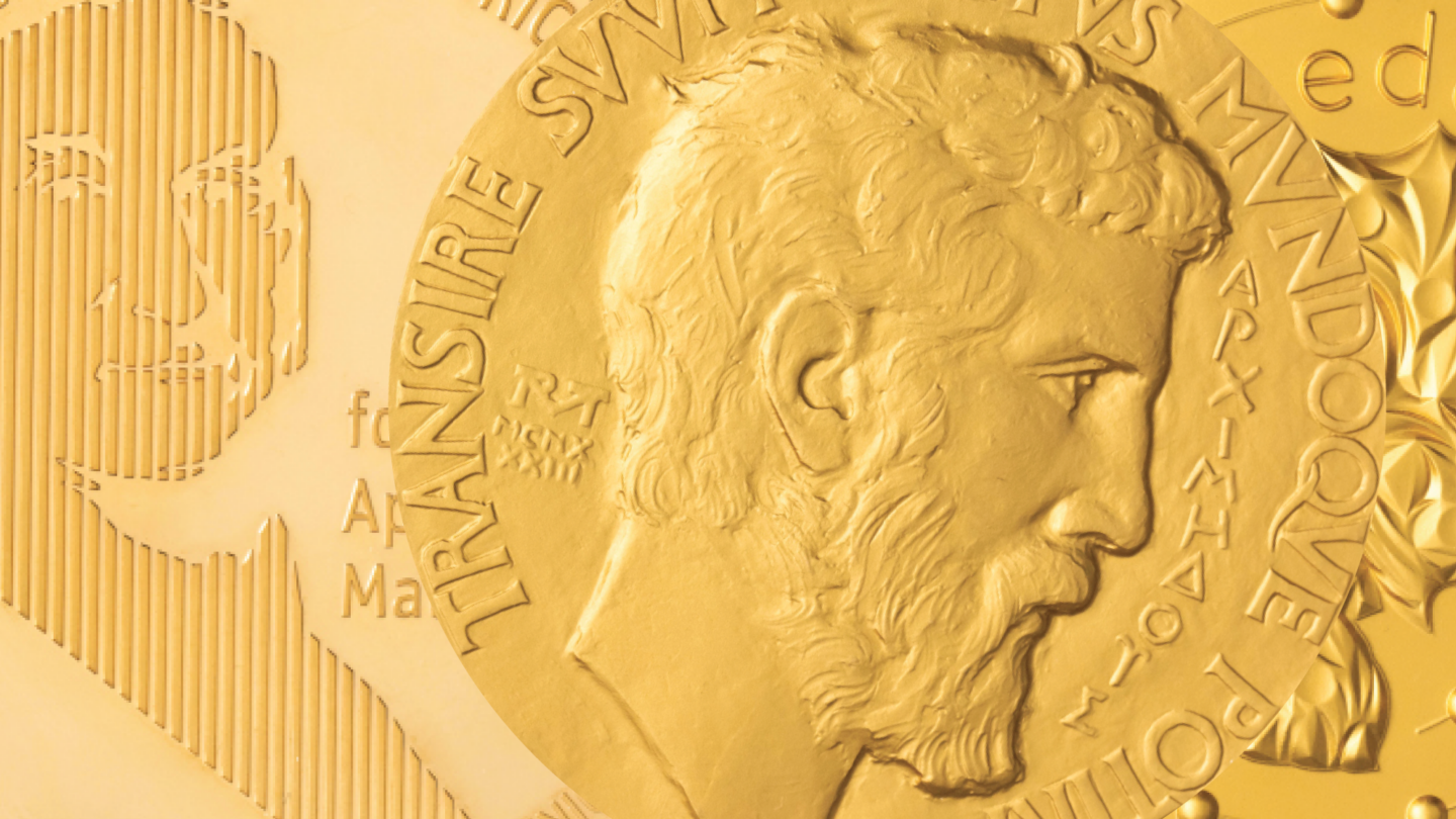 Close-up of gold medals with embossed profiles and text, featuring a bearded man in profile on the foreground medal, with overlapping designs and inscriptions visible in the background.