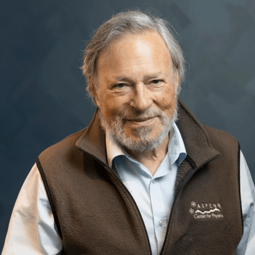 An older man with a gray beard smiles, wearing a brown fleece vest with the Aspen Center for Physics logo.