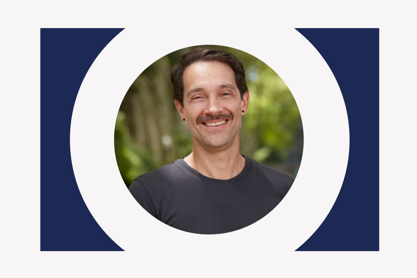 A man with a mustache smiling in a circular frame.