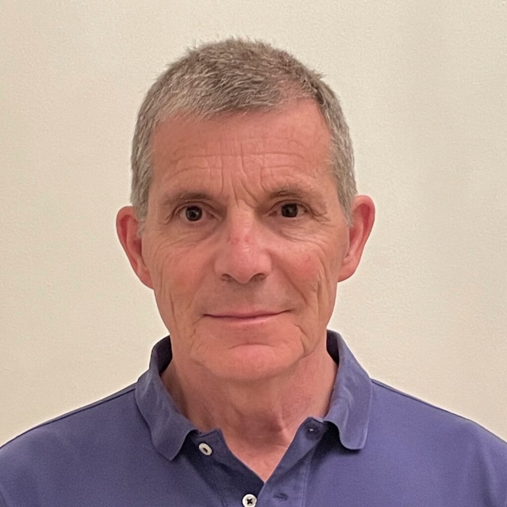 A middle-aged man with short grey hair wearing a blue polo shirt.