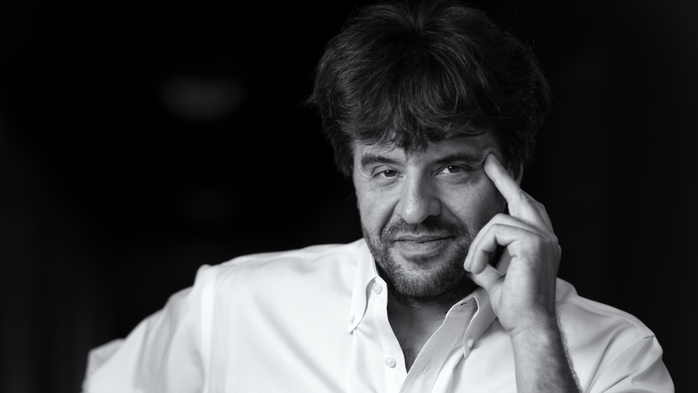 A portrait of Karl Deisseroth touching his hand to his head.