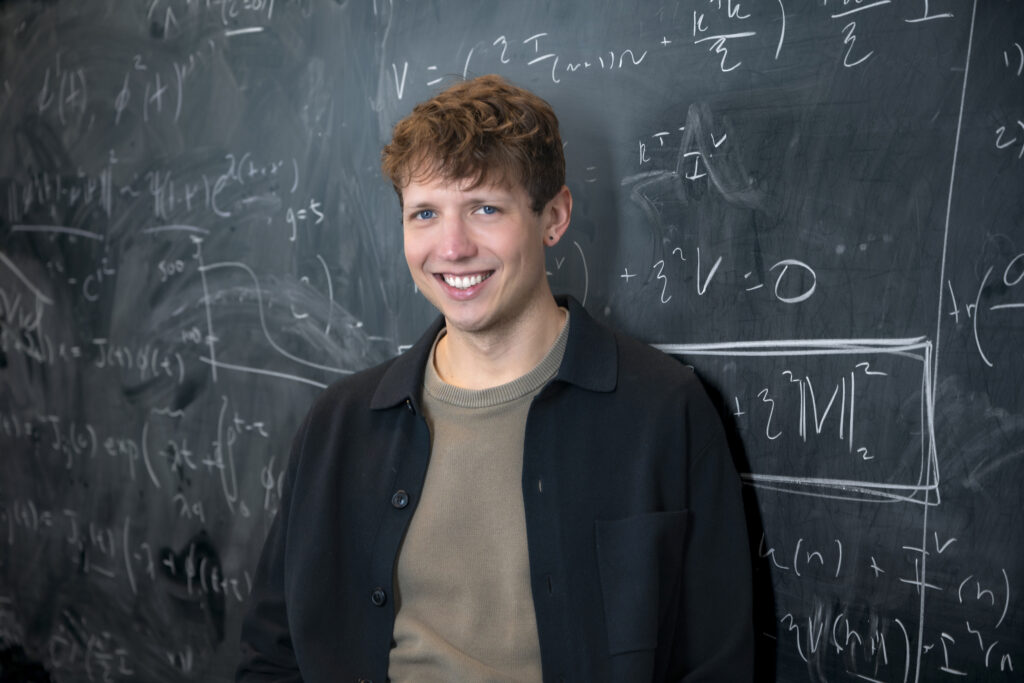 Photo of David G. Clark in front of a chalkboard.