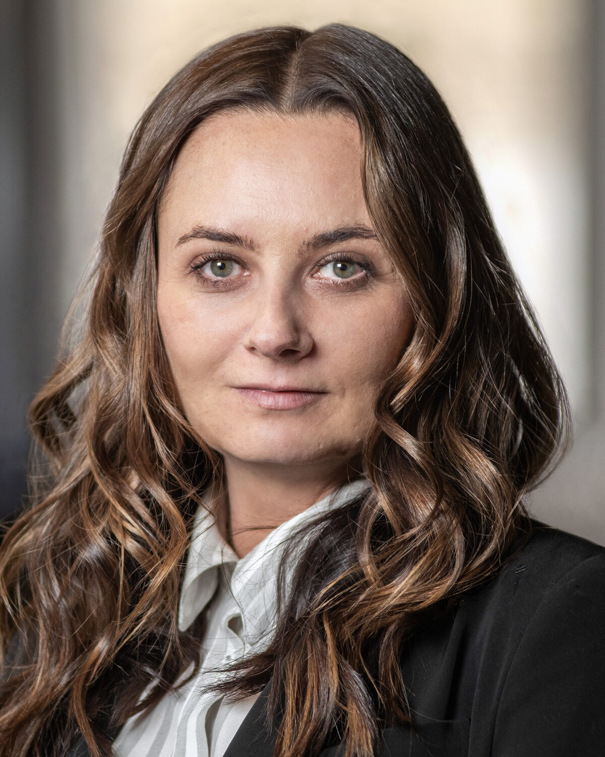 A headshot of a woman wearing a white collared shirt and a black blazer.