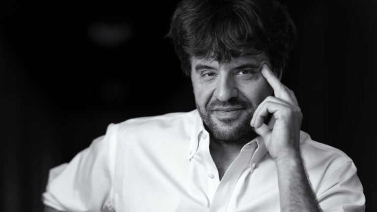 A portrait of Karl Deisseroth touching his hand to his head.