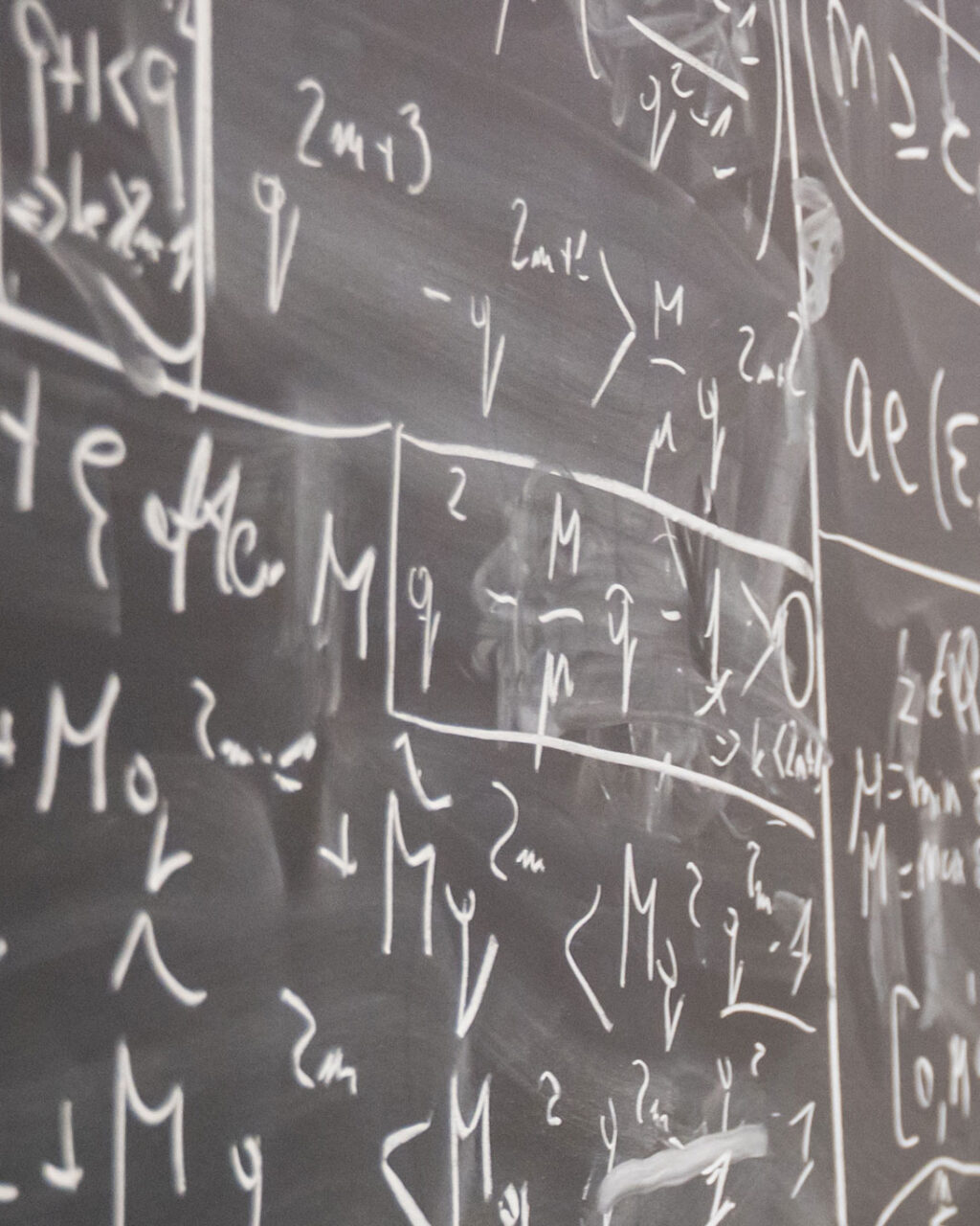 A chalkboard covered in complex handwritten mathematical equations and inequalities.