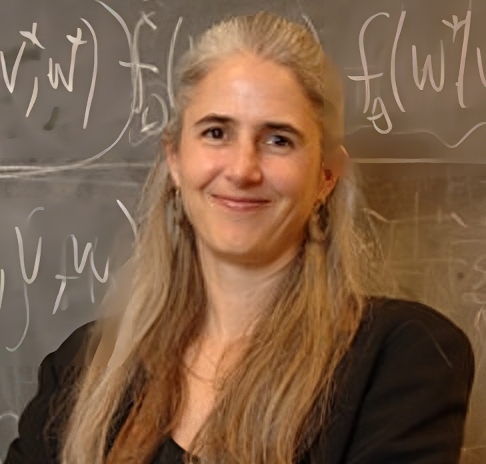 A woman with long grey hair smiling in front of a chalkboard covered in mathematical equations.