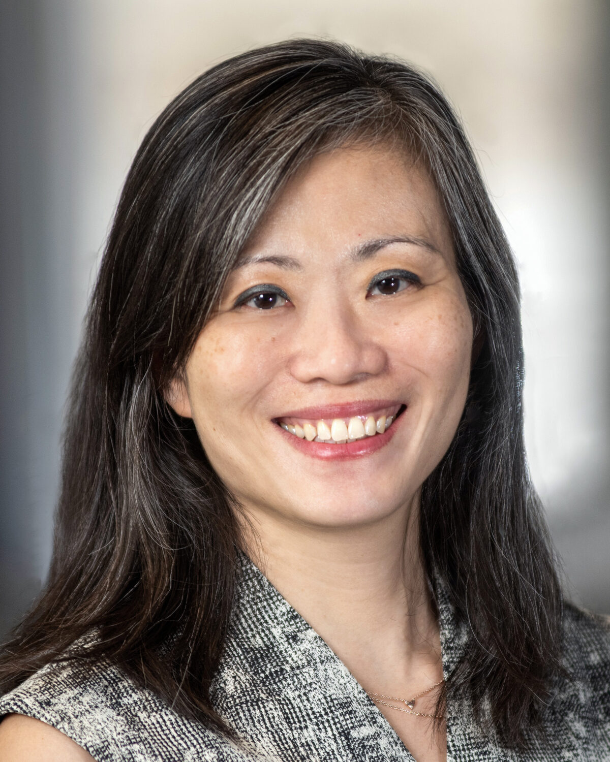 A professional headshot of a smiling woman with dark, shoulder-length hair.