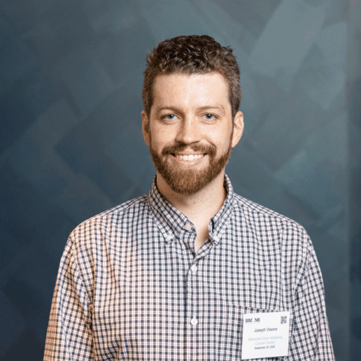 A smiling man with a beard wearing a plaid shirt and a name tag that reads, Joseph Visone, Memorial Sloan Kettering Cancer Center.